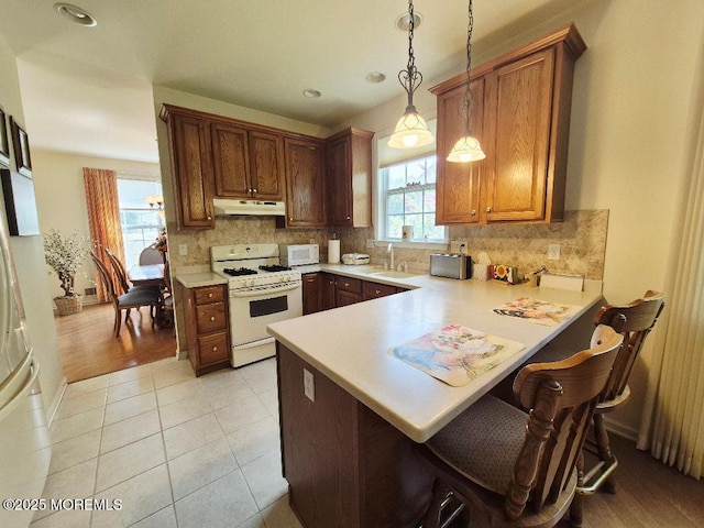 17 Marigold Ln, Little Egg Harbor, NJ 08087 - kitchen with white gas range oven, under cabinet range hood, light countertops, a peninsula, and pendant lighting