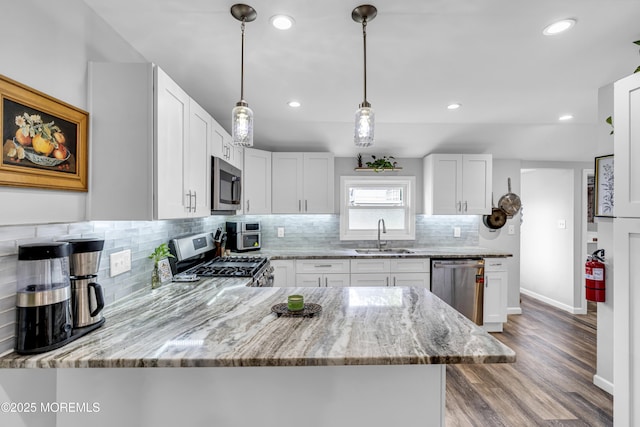 208 Hilltop Blvd, Cliffwood, NJ 07735 - kitchen featuring appliances with stainless steel finishes, backsplash, light stone counters, wood finished floors, and hanging light fixtures