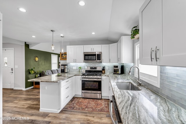208 Hilltop Blvd, Cliffwood, NJ 07735 - kitchen with appliances with stainless steel finishes, a peninsula, vaulted ceiling, white cabinetry, and tasteful backsplash
