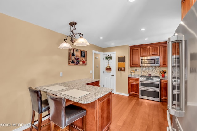 1617 Doris St, Wall, NJ 07719 - kitchen featuring appliances with stainless steel finishes, a peninsula, light wood-type flooring, backsplash, and recessed lighting