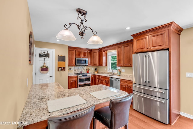 1617 Doris St, Wall, NJ 07719 - kitchen with premium appliances, brown cabinetry, light wood-style flooring, recessed lighting, and a kitchen breakfast bar