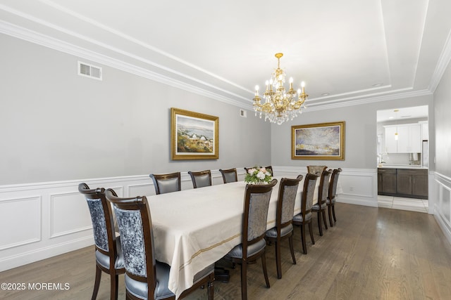 94 Bradhurst Ave, Lakewood, NJ 08701 - dining space featuring a chandelier, wood finished floors, a decorative wall, a raised ceiling, and crown molding