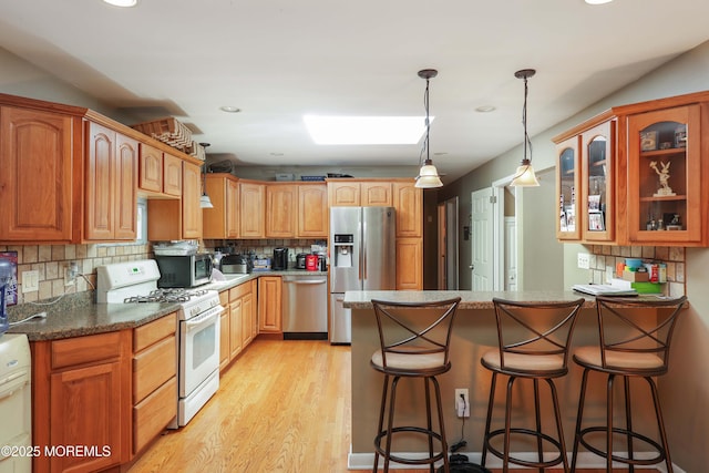 8 N Cherokee Ln, Brick, NJ 08724 - kitchen featuring stainless steel appliances, glass insert cabinets, light wood-type flooring, a breakfast bar area, and a peninsula
