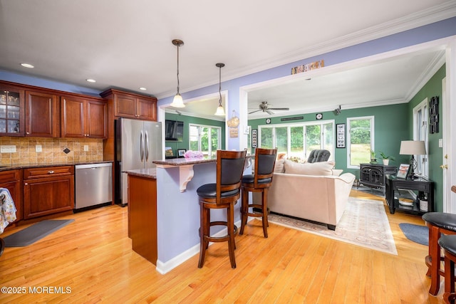 2 Darien Cir, Howell, NJ 07731 - kitchen featuring appliances with stainless steel finishes, a breakfast bar, light wood-style flooring, crown molding, and decorative backsplash