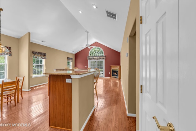 12 Drayton Rd, Manchester, NJ 08759 - kitchen with ceiling fan, a breakfast bar area, light wood-style floors, vaulted ceiling, and a lit fireplace