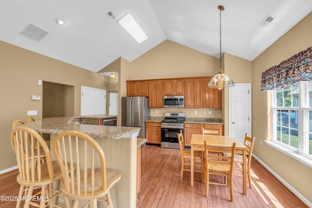 12 Drayton Rd, Manchester, NJ 08759 - kitchen featuring stainless steel appliances, high vaulted ceiling, a kitchen bar, brown cabinets, and light wood-style flooring