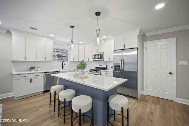 12 Weston Ct, Marlboro, NJ 07746 - kitchen featuring stainless steel appliances, a kitchen breakfast bar, crown molding, light wood-style floors, and white cabinets