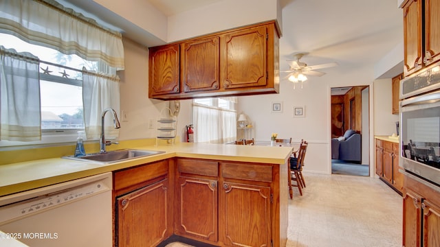 20 Kenwood Ln, Old Bridge, NJ 08857 - kitchen featuring dishwasher, ceiling fan, a peninsula, brown cabinetry, and healthy amount of natural light