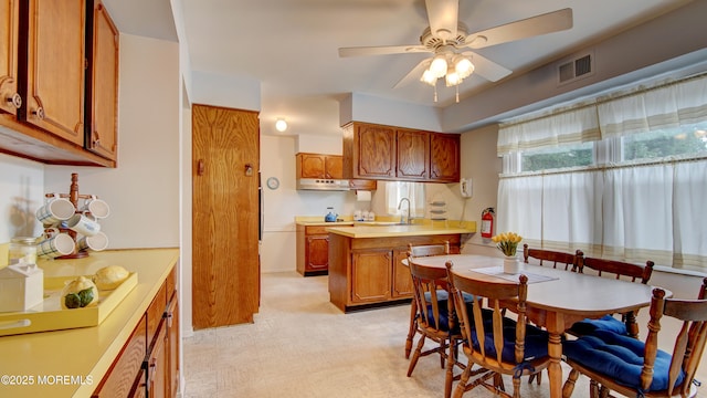 20 Kenwood Ln, Old Bridge, NJ 08857 - kitchen featuring brown cabinetry, a peninsula, under cabinet range hood, a ceiling fan, and light countertops