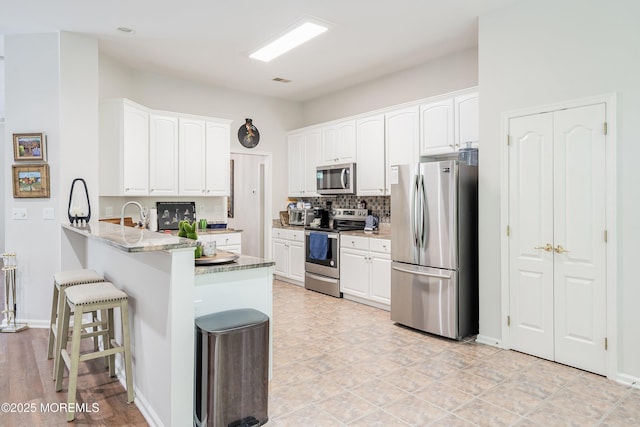 1 Silverspring Dr, Lakewood, NJ 08701 - kitchen featuring appliances with stainless steel finishes, a peninsula, a kitchen bar, and white cabinets
