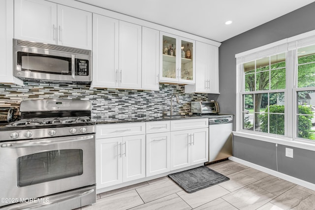 18 Remington Dr Unit 5, Freehold, NJ 07728 - kitchen featuring appliances with stainless steel finishes, tasteful backsplash, white cabinetry, dark stone counters, and glass insert cabinets