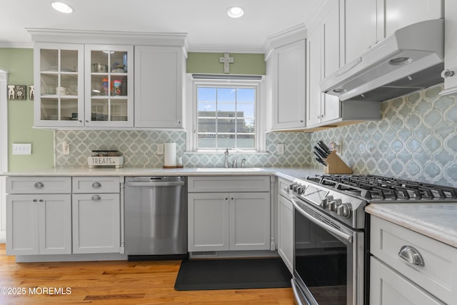 623 Forecastle Ave, Beachwood, NJ 08722 - kitchen featuring stainless steel appliances, under cabinet range hood, light wood-type flooring, ornamental molding, and glass insert cabinets
