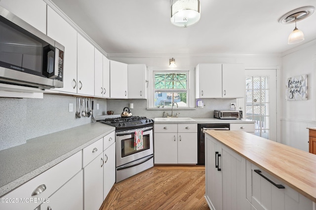 505 Moore Rd, Neptune Township, NJ 07753 - kitchen featuring stainless steel appliances, decorative backsplash, light wood-style floors, white cabinets, and crown molding
