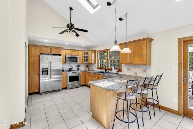40 Centerville Rd, Holmdel, NJ 07733 - kitchen with stainless steel appliances, vaulted ceiling, a peninsula, brown cabinetry, and plenty of natural light
