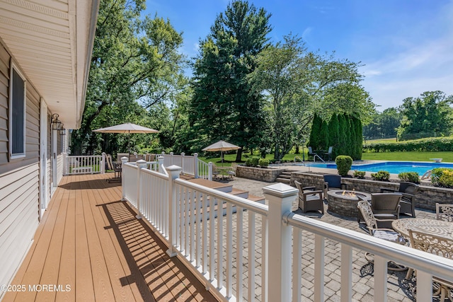 40 Centerville Rd, Holmdel, NJ 07733 - wooden terrace with an outdoor pool, an outdoor fire pit, outdoor dining space, view of wooded area, and a patio