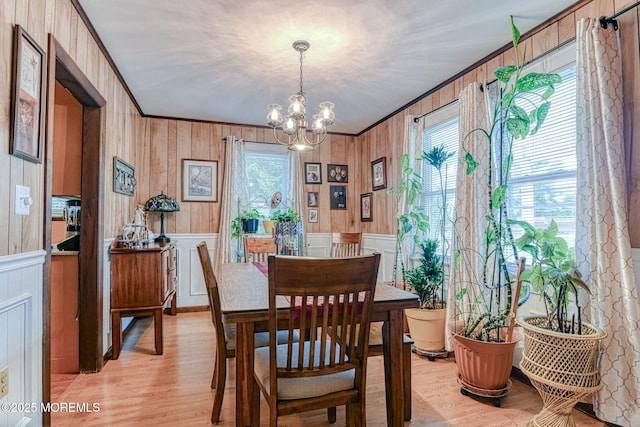 198 W Sylvania Ave, Neptune City, NJ 07753 - dining area with healthy amount of natural light, ornamental molding, light wood finished floors, a chandelier, and wood walls