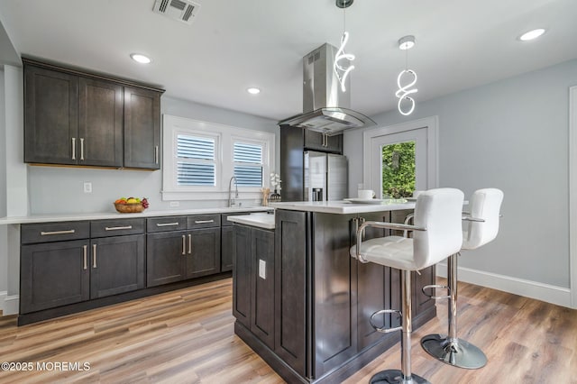 101 Broad St, Matawan, NJ 07747 - kitchen featuring island range hood, stainless steel refrigerator with ice dispenser, a kitchen breakfast bar, light countertops, and dark brown cabinets