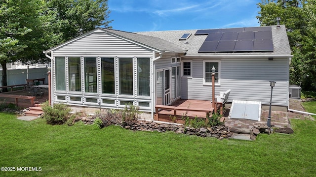 962 Columbus Dr, Brick, NJ 08724 - rear view of house featuring a sunroom, a wooden deck, a shingled roof, solar panels, and a yard