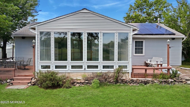 962 Columbus Dr, Brick, NJ 08724 - back of property with a deck, roof mounted solar panels, a sunroom, a lawn, and a shingled roof