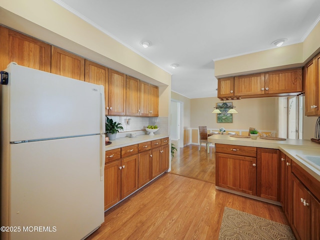 962 Columbus Dr, Brick, NJ 08724 - kitchen with freestanding refrigerator, brown cabinets, light countertops, light wood finished floors, and ornamental molding