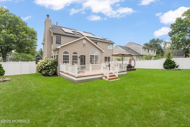 95 Linden Ave, West Long Branch, NJ 07764 - rear view of house featuring a fenced backyard, a chimney, a deck, and roof mounted solar panels