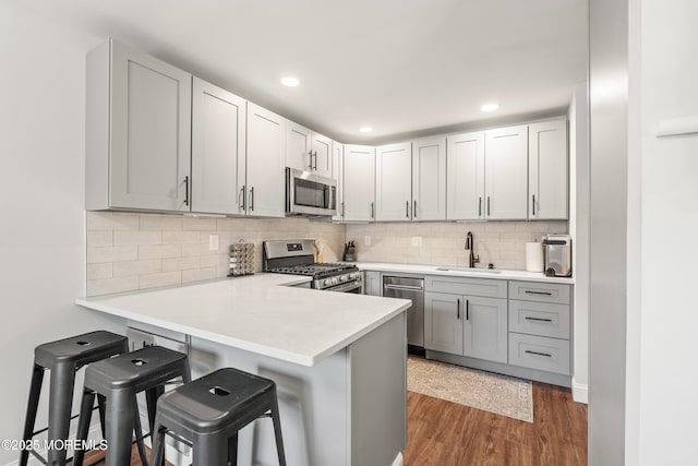 50 Lenape Trl, Tinton Falls, NJ 07724 - kitchen featuring stainless steel appliances, a breakfast bar area, wood finished floors, light countertops, and a peninsula