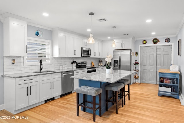 410 Jamaica Blvd, Toms River, NJ 08757 - kitchen featuring appliances with stainless steel finishes, a breakfast bar area, ornamental molding, white cabinets, and light wood-style flooring