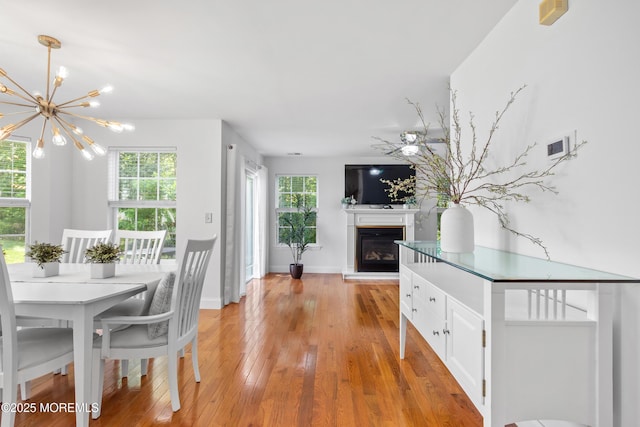 9 Nutmeg Ct, Tinton Falls, NJ 07753 - dining space with light wood-style flooring, a chandelier, and a glass covered fireplace
