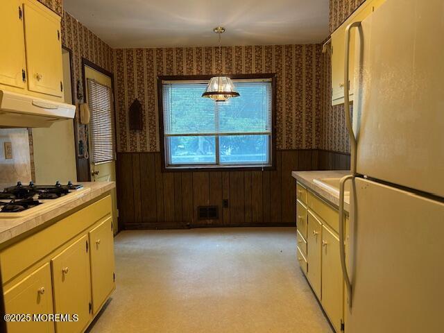 1599 Woodcrest Dr, Toms River, NJ 08753 - kitchen with white appliances, wallpapered walls, under cabinet range hood, a wainscoted wall, and light countertops