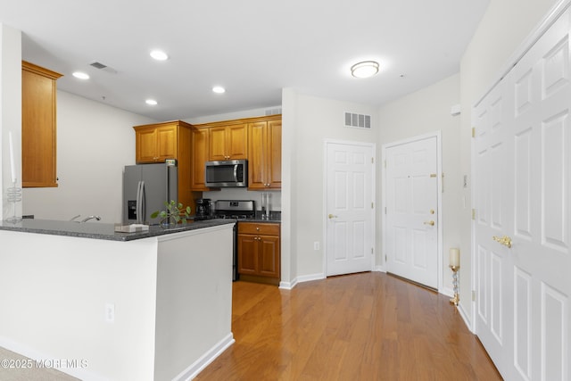 428 Sophee Ln, Lakewood, NJ 08701 - kitchen with appliances with stainless steel finishes, brown cabinetry, light wood-type flooring, recessed lighting, and dark stone counters
