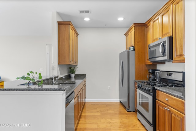 428 Sophee Ln, Lakewood, NJ 08701 - kitchen featuring appliances with stainless steel finishes, a peninsula, light wood-type flooring, dark stone counters, and brown cabinets