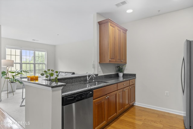 428 Sophee Ln, Lakewood, NJ 08701 - kitchen featuring stainless steel appliances, light wood-style flooring, dark stone countertops, brown cabinetry, and a peninsula
