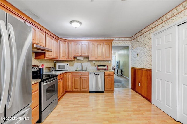 128 Korn Market Unit E, Freehold, NJ 07728 - kitchen with stainless steel appliances, under cabinet range hood, wallpapered walls, a wainscoted wall, and light wood-type flooring