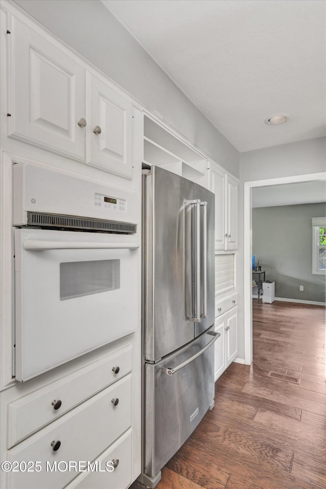 25 Forman Ln, Manalapan, NJ 07726 - kitchen with high quality fridge, oven, white cabinets, and dark wood-style floors