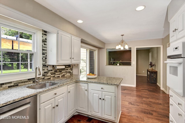 25 Forman Ln, Manalapan, NJ 07726 - kitchen featuring oven, stainless steel dishwasher, a chandelier, backsplash, and a peninsula