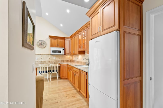 7 Lorraine Ct, East Brunswick, NJ 08816 - kitchen featuring white appliances, light stone counters, light wood-style floors, lofted ceiling, and glass insert cabinets