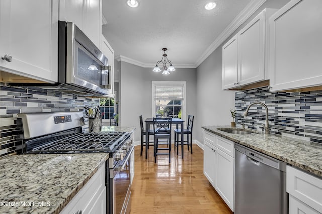 1602 Wagon Wheel Ct, Freehold, NJ 07728 - kitchen featuring appliances with stainless steel finishes, backsplash, white cabinets, crown molding, and a chandelier