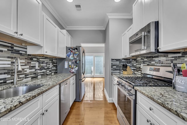 1602 Wagon Wheel Ct, Freehold, NJ 07728 - kitchen with appliances with stainless steel finishes, light wood-style flooring, crown molding, white cabinets, and backsplash