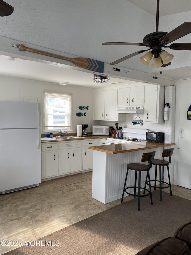 25 E 49th St, Long Beach Twp, NJ 08008 - kitchen with white appliances, under cabinet range hood, a peninsula, ceiling fan, and white cabinets