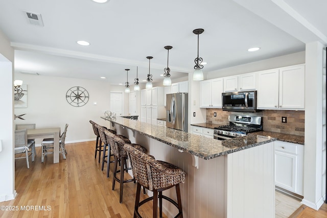 507 Amber St Unit B, Beach Haven, NJ 08008 - kitchen with stainless steel appliances, backsplash, white cabinetry, a breakfast bar, and dark stone countertops