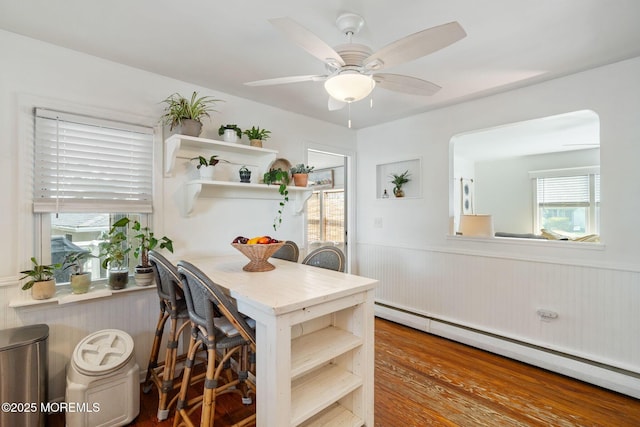 529 Smith Dr, Point Pleasant, NJ 08742 - dining space featuring baseboard heating, a wainscoted wall, a ceiling fan, wood finished floors, and arched walkways