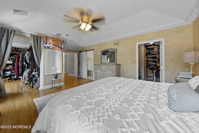 6 Tower Ct, Farmingdale, NJ 07727 - bedroom with a spacious closet, wood-type flooring, a barn door, crown molding, and a tray ceiling