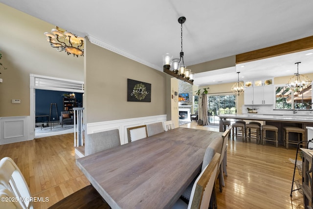 6 Tower Ct, Farmingdale, NJ 07727 - dining space with a chandelier, a large fireplace, wainscoting, light wood-style flooring, and a decorative wall