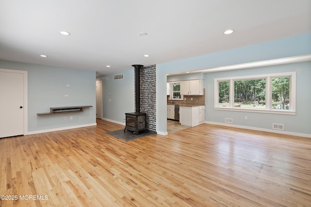 271 S Stump Tavern Rd, Jackson, NJ 08527 - unfurnished living room featuring a wood stove, light wood finished floors, and recessed lighting