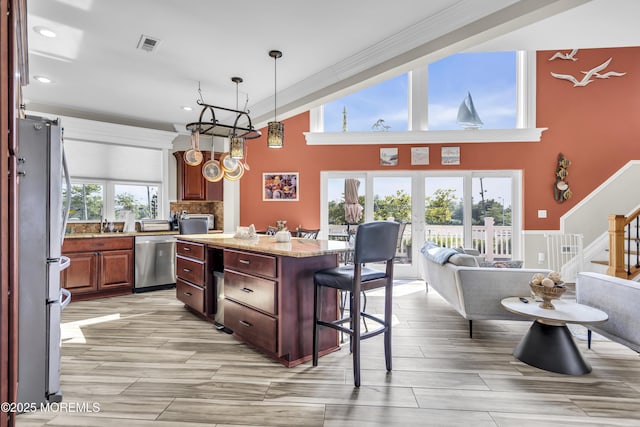 36 Joy Rd, Manahawkin, NJ 08050 - kitchen featuring appliances with stainless steel finishes, a center island, a towering ceiling, a breakfast bar, and light stone counters