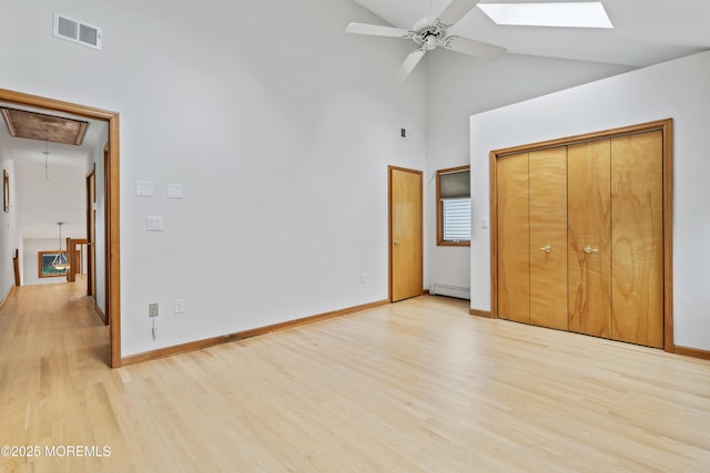 24 Bray Ave, North Middletown, NJ 07748 - unfurnished bedroom featuring attic access, light wood-style flooring, high vaulted ceiling, a skylight, and a baseboard radiator