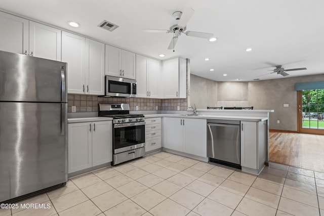 24 Bray Ave, North Middletown, NJ 07748 - kitchen featuring stainless steel appliances, ceiling fan, light countertops, a peninsula, and decorative backsplash