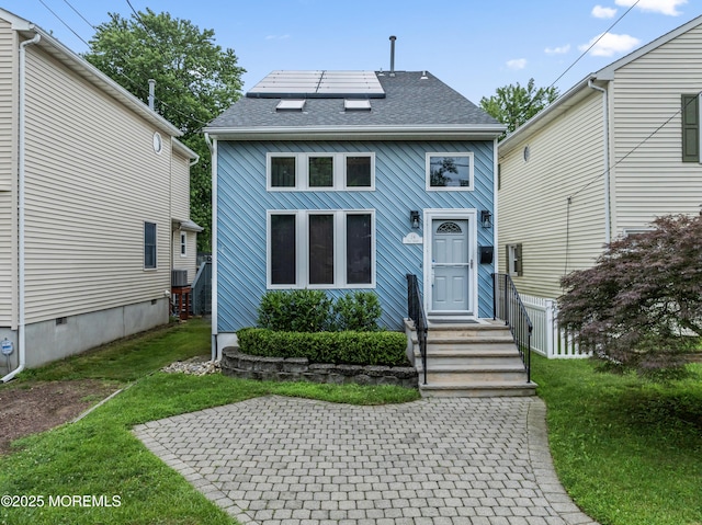 24 Bray Ave, North Middletown, NJ 07748 - view of front facade featuring roof mounted solar panels, roof with shingles, and a front lawn