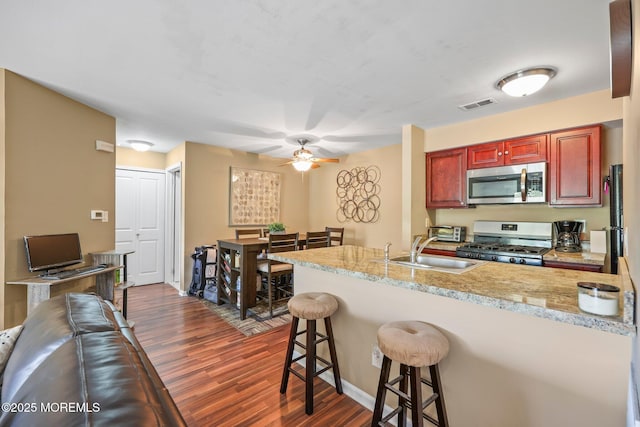 147 Longfield Ct # 147, East Brunswick, NJ 08816 - kitchen with stainless steel microwave, gas range, dark wood-style flooring, and a peninsula