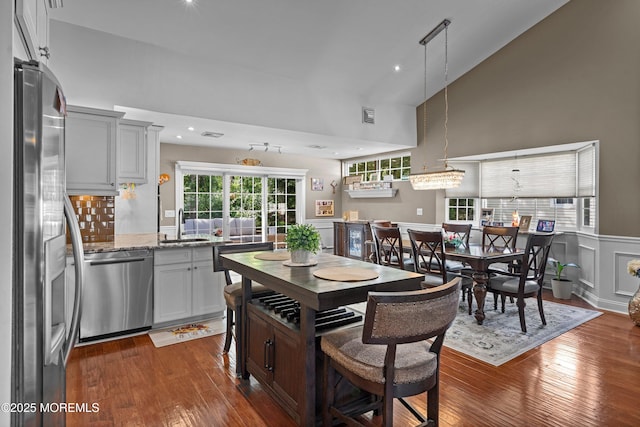 98 Yorkwood Dr, Brick, NJ 08723 - kitchen with stainless steel appliances, high vaulted ceiling, dark wood finished floors, light stone counters, and a wainscoted wall